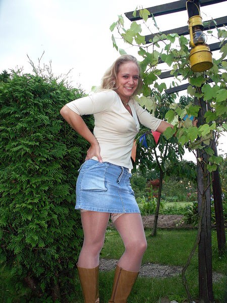 Hausfrau in Minirock und Strümpfen im Garten (nicht nackt). 