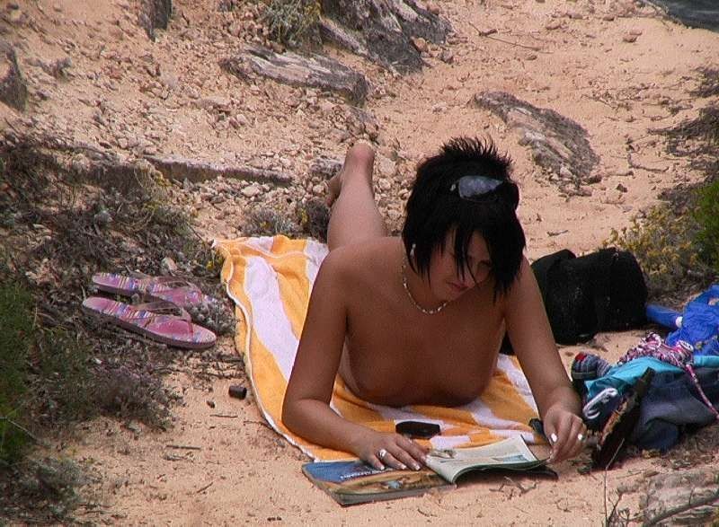Scharfe Spanner-Fotos einer jungen Frau, die sich beim FKK-Sonnenbad am Str...